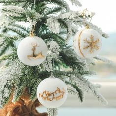 three ornaments hanging from a christmas tree in front of a window with snow on the branches