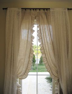 an open window with white curtains in front of it and a stone path leading to the outside