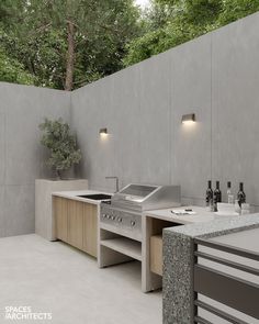 an outdoor kitchen with stainless steel appliances and counter tops, built into the side of a concrete wall