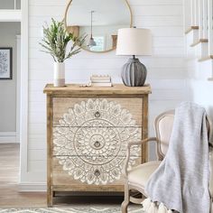 a white and wood dresser with a mirror above it next to a chair in a living room