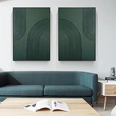 two paintings hang on the wall above a couch and coffee table in a living room