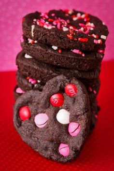 chocolate cookies with pink and white sprinkles are stacked on top of each other