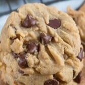 a chocolate chip cookie sitting on top of a wooden cutting board