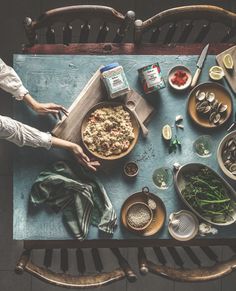 a table topped with lots of food on top of a blue counter next to a wooden chair