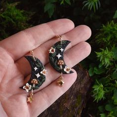 a pair of black and gold earrings with stars on them sitting in someone's hand