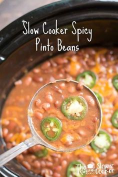 a ladle full of beans and green peppers in a slow cooker filled with chili