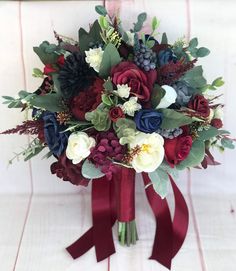 a bridal bouquet with red, white and blue flowers on a burgundy ribbon tied around it