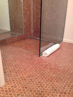 a roll of toilet paper sitting on the ground in front of a shower stall door