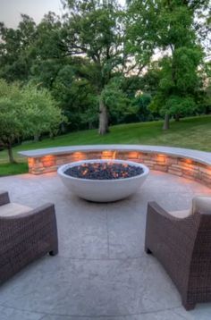 an outdoor fire pit surrounded by wicker furniture