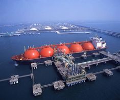 an oil rig in the middle of water with large orange tanks on it's side