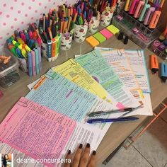 many different colored pens and paper on a table with writing utensils next to them