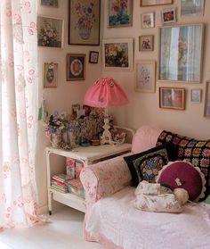 a living room filled with lots of pictures on the wall and a pink lamp in the corner