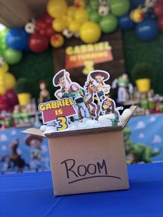 a cardboard box that has some stickers on it and is sitting on a table with balloons in the background