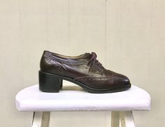 "* Classic wingtip brogues with perforations * Dark brown leather * Tapered round toe * Chunky stacked heel * All leather insole and lining, sole is combination of leather and texturized, non-slip rubber * 5 eyelet lace-up Label: Kenneth Cole New York Stamped: 6 1/2 - Mde in Brazil Excellent condition. Appear barely worn. Well cared-for shoes with light wear and creasing. Inside Length: 9 3/8\" Outer Ball Width: 3\" Heel: 2\" To be certain of fit, measure a pair of your own shoes across the ball Vintage Almond Toe Lace-up Work Shoes, Vintage Oxford Oxfords For Office, Vintage Oxfords For Office, Vintage Leather Brogue Shoes For Work, Vintage Lace-up Leather Office Shoes, Vintage Lace-up Leather Shoes For Office, Vintage Leather Lace-up Shoes For Office, Wingtip Shoes, Lit Shoes