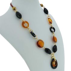 This gorgeous contemporary Murano Glass necklace in golden brown and black color palette features an exquisite design of concentric rings in the center suspended from a beaded necklace. This Italian necklace is an example of unique hand-made Murano Glass jewelry that demonstrates why Murano glass makers have been held in high regard around the world for ages. This versatile piece of Italian jewelry can be worn with your evening or casual outfits and will add Venetian elegance and Italian style t Elegant Brown Round Beaded Necklace, Elegant Brown Round Beaded Necklaces, Elegant Brown Round Necklace, Elegant Brown Round Necklaces, Elegant Long Brown Necklace, Italian Necklace, Black Color Palette, Italian Leather Handbags, Murano Glass Necklaces