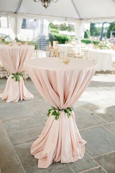 the tables are covered with pink cloths and green leaves on them for an elegant look