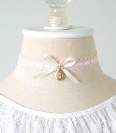 This sweet choker necklace is handmade with a scalloped edge lace in a soft blush pink. An ivory white silk satin ribbon is woven through the lace and features a pretty bow with small vintage pearl beads. A unique and rare vintage brass locket hangs from the bow. Take a peek at the close up photos showing the beautiful painted floral enamel design. A lovely jewelry accessory for women who love Victorian and Regency Era styles. * Size ~ Adjustable length 12 - 15 inches (3 inch extender chain)  Pl Elegant White Jewelry With Pink Bow, Lace Trim Choker Jewelry Gift, Pink Ribbon Wedding Jewelry, Delicate Pink Choker For Gift, Vintage Lace Choker As A Gift, Vintage Lace Choker For Gifts, Vintage White Choker For Gift, Lace Choker With Lace Trim As Gift, Cute White Jewelry With Ribbon