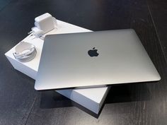 an apple laptop sitting on top of a wooden table next to a charger and power adapter