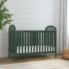 a green crib next to a potted plant in a room with white walls