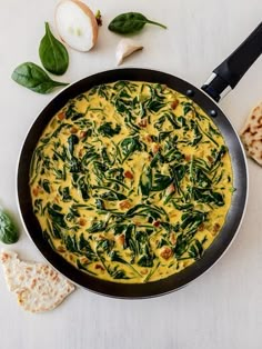 an omelet with spinach and cheese in a pan next to crackers