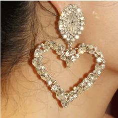 the back of a woman's ear with a pair of heart shaped earrings