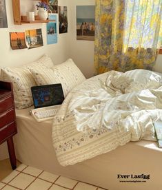 a laptop computer sitting on top of a bed in a room with yellow drapes