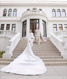 two women in white dresses are standing on the steps outside a large building with stairs leading up to it