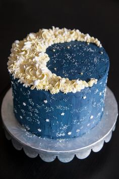 a blue cake with white frosting and sprinkles sits on a plate