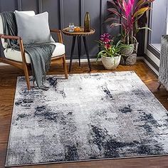 a living room area with a rug, chair and potted plants on the floor