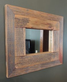 a wooden mirror hanging on the wall in a room with gray walls and wood trimmings