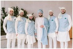 a group of men standing next to each other wearing blue and white outfits with turbans