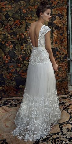 a woman in a wedding dress standing on a rug with an ornate wall behind her