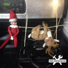 two stuffed animals are hanging on clothes pins in front of an oven with the door open