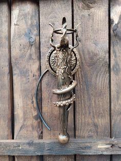 an ornate metal hook on the side of a wooden fence with a statue in it