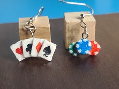 two pairs of earrings with playing cards dangling from them on top of a wooden block