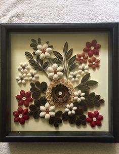 an art piece with flowers and leaves in a black frame