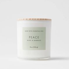 a white candle with a wooden lid that says peace on the front and side of it