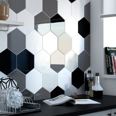 a black and white tiled wall in a kitchen next to a counter with utensils on it