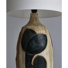 a wooden table lamp with black and white designs on the base, next to a light shade