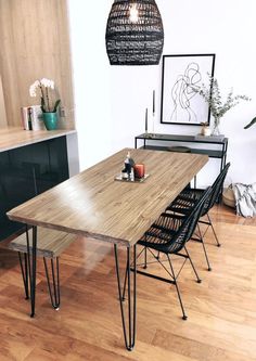 a dining room table and chairs in front of a wall with art work on it