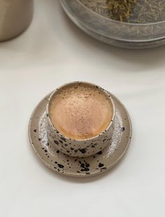 a cup of coffee sitting on top of a saucer next to a bowl filled with tea