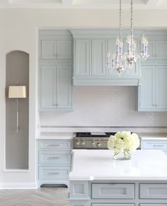 a large kitchen with blue cabinets and white counter tops, chandelier hanging from the ceiling