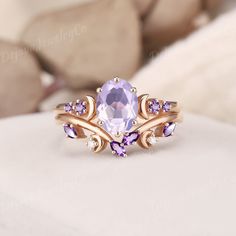 a ring with an amethorate and purple stones in it on a white surface