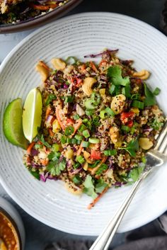 a white plate topped with rice salad next to two bowls filled with sauce and lime wedges