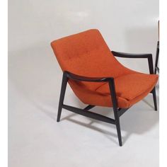 an orange chair sitting on top of a white floor next to a black framed object