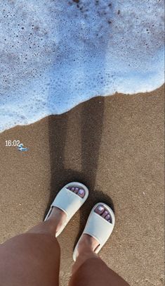 a person standing on the beach with their feet in the sand