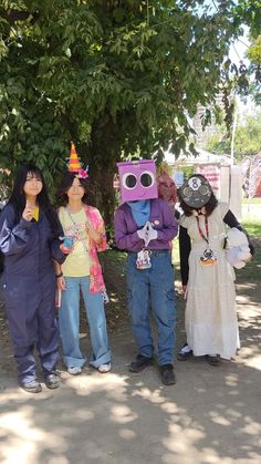 four people in costumes standing under a tree