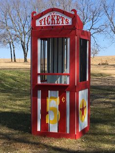 a red ticket booth sitting in the middle of a field