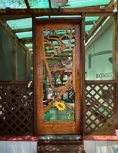 a wooden door sitting inside of a glass covered porch next to a fence and trees