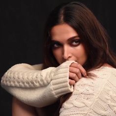 a woman with long hair wearing a white sweater and holding her arm over her shoulder